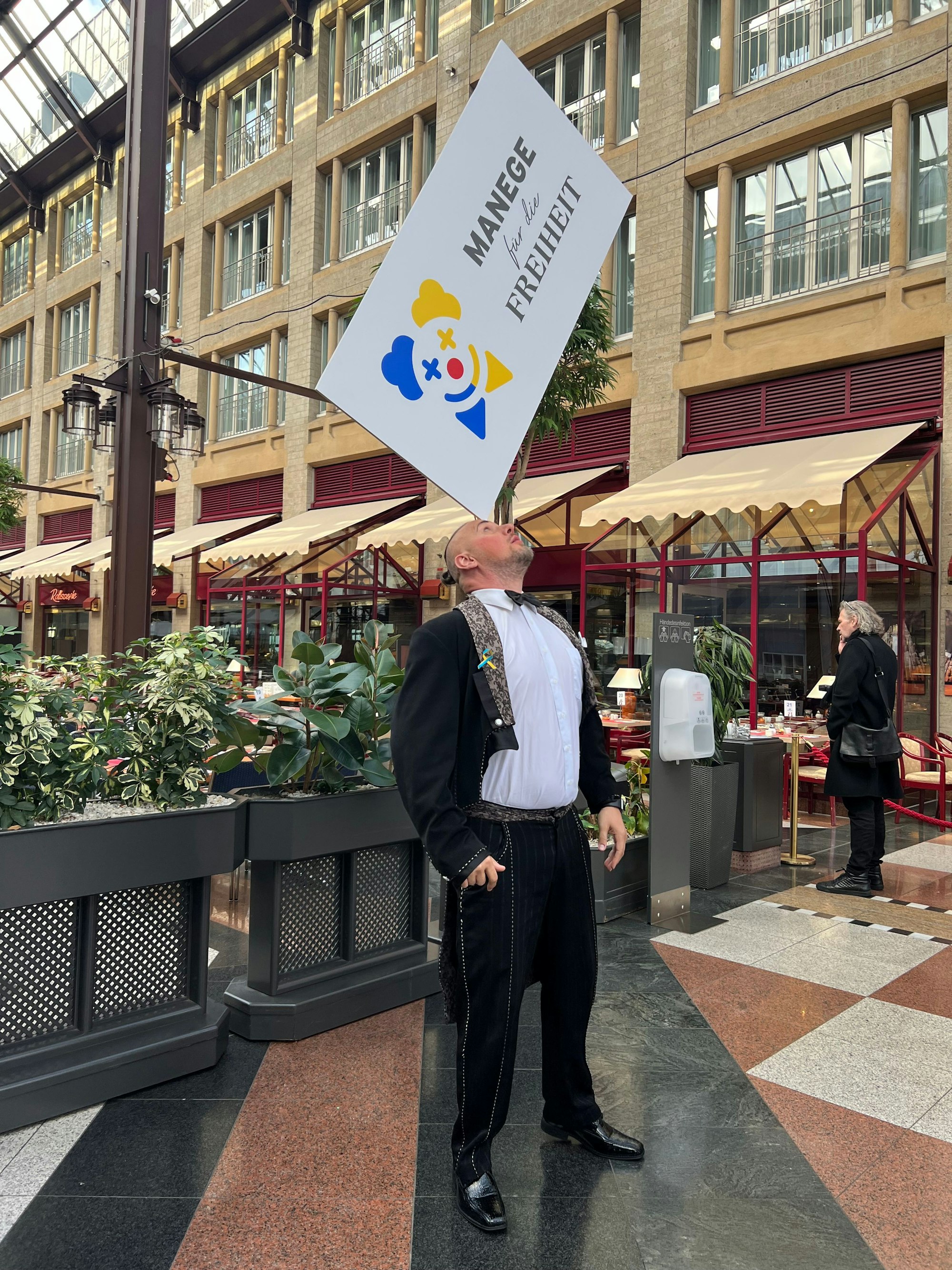 Der ukrainische Zirkuskünstler Georgii Kyrychenko balanciert im Kölner Maritim Hotel das Organisationsschild von „Manege für die Freiheit“ auf der Stirn.