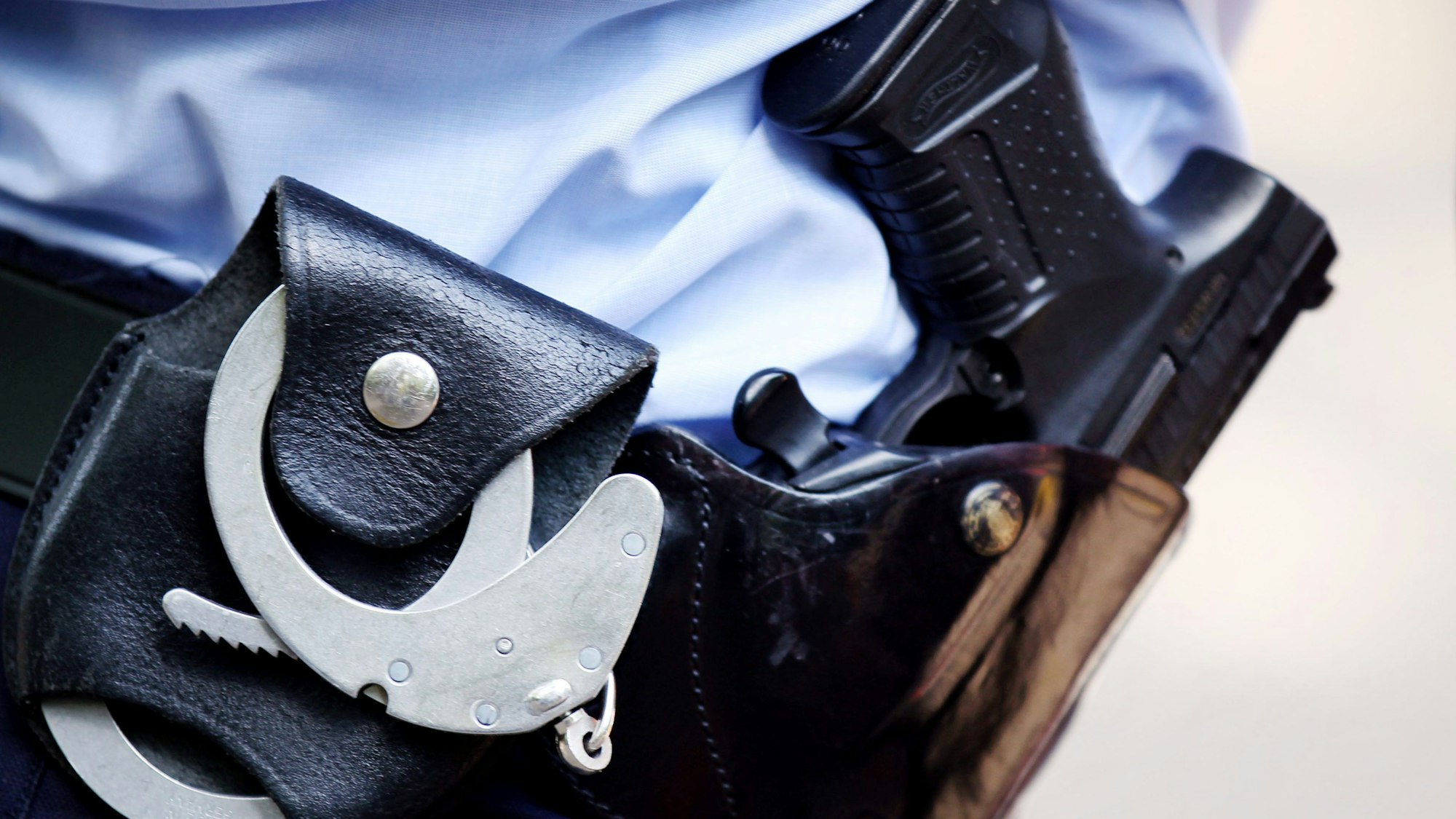 Ein Polizist mit Handschellen und Pistole (Symbolbild)