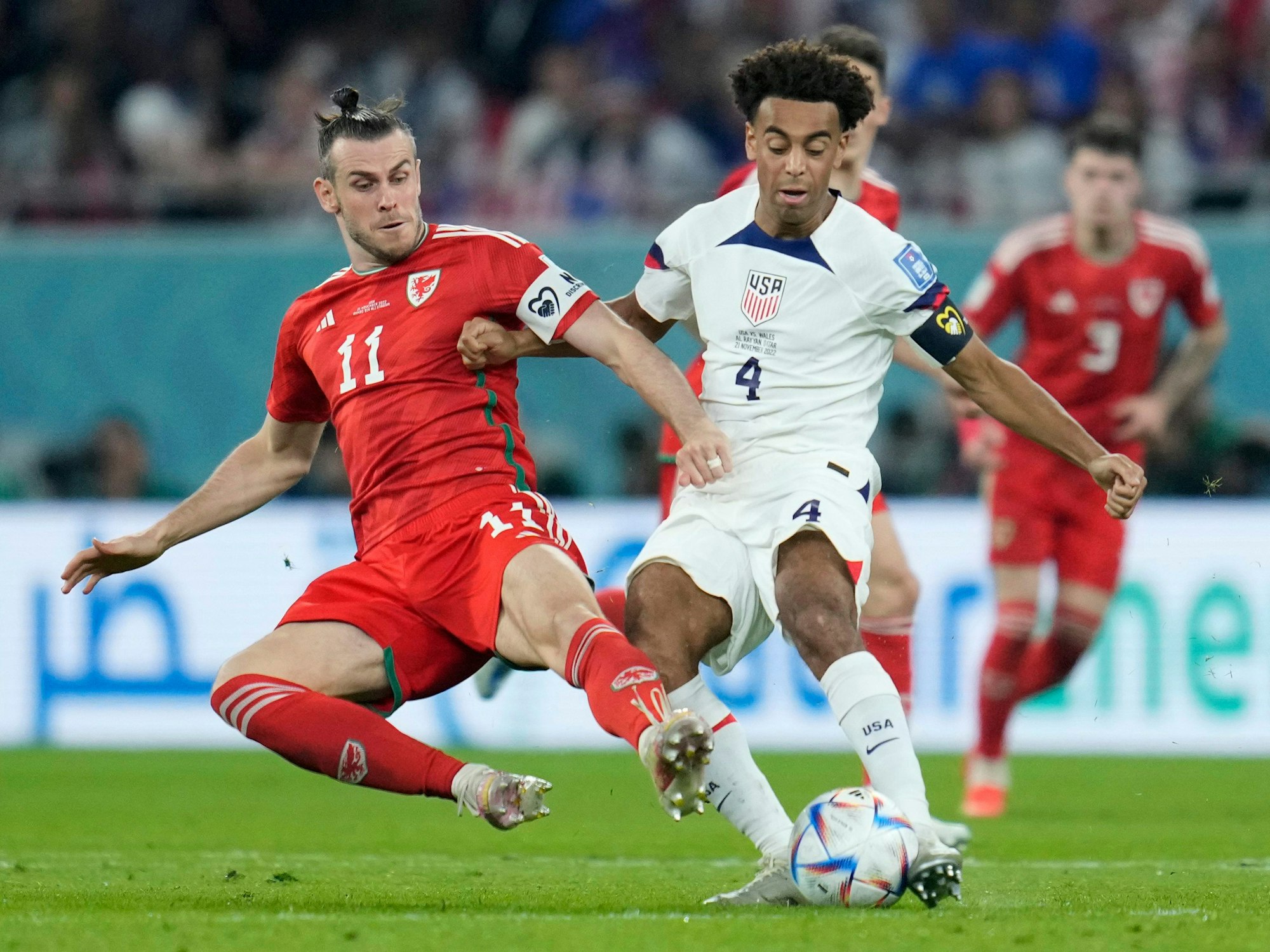 Wales' Gareth Bale, left, challenges for the ball with Tyler Adams of the United States during the World Cup, group B soccer match between the United States and Wales, at the Ahmad Bin Ali Stadium in Doha, Qatar, Monday, Nov. 21, 2022. (AP Photo/Ashley Landis)