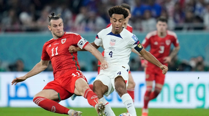 Wales' Gareth Bale, left, challenges for the ball with Tyler Adams of the United States during the World Cup, group B soccer match between the United States and Wales, at the Ahmad Bin Ali Stadium in Doha, Qatar, Monday, Nov. 21, 2022. (AP Photo/Ashley Landis)