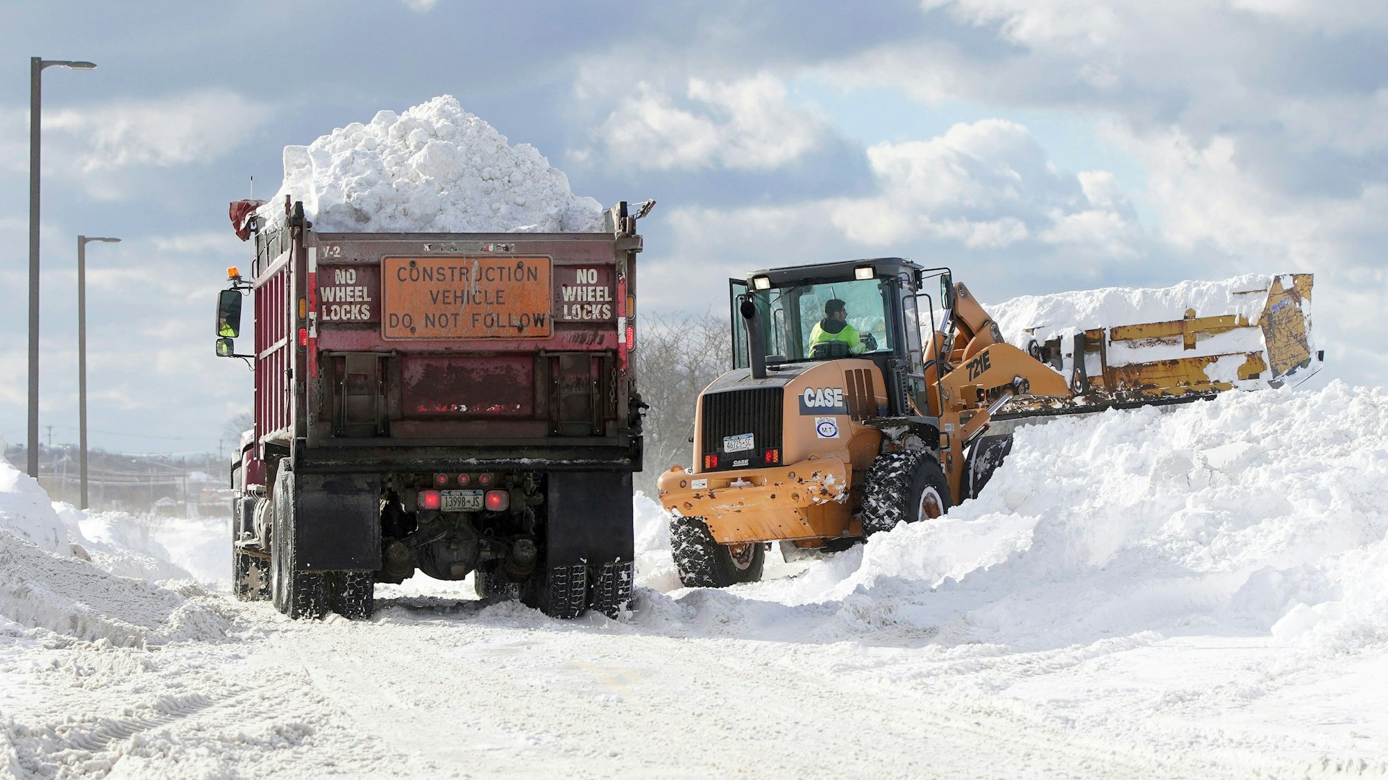 Lastwagen laden Schnee auf einem Parkplatz ab.