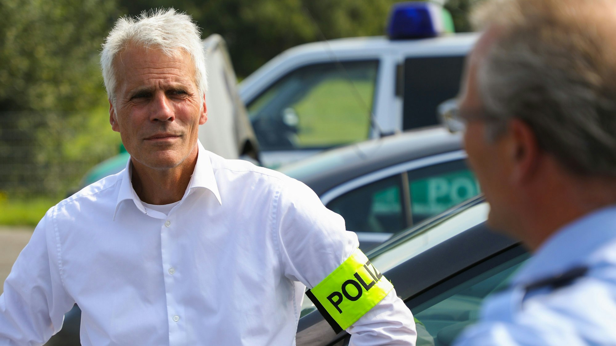 Dirk Weinspach ist bei einem Einsatz zu sehen. Er trägt ein weißes Hemd und eine neongelbe Polizei-Binde am Arm.