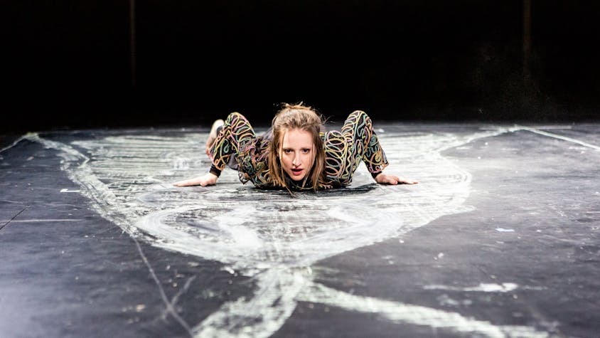Die Schauspielerin Kristin Steffen liegt auf einem schwarzen Boden, der mit weißer Kreide bemalt ist.