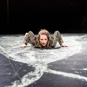 Die Schauspielerin Kristin Steffen liegt auf einem schwarzen Boden, der mit weißer Kreide bemalt ist.