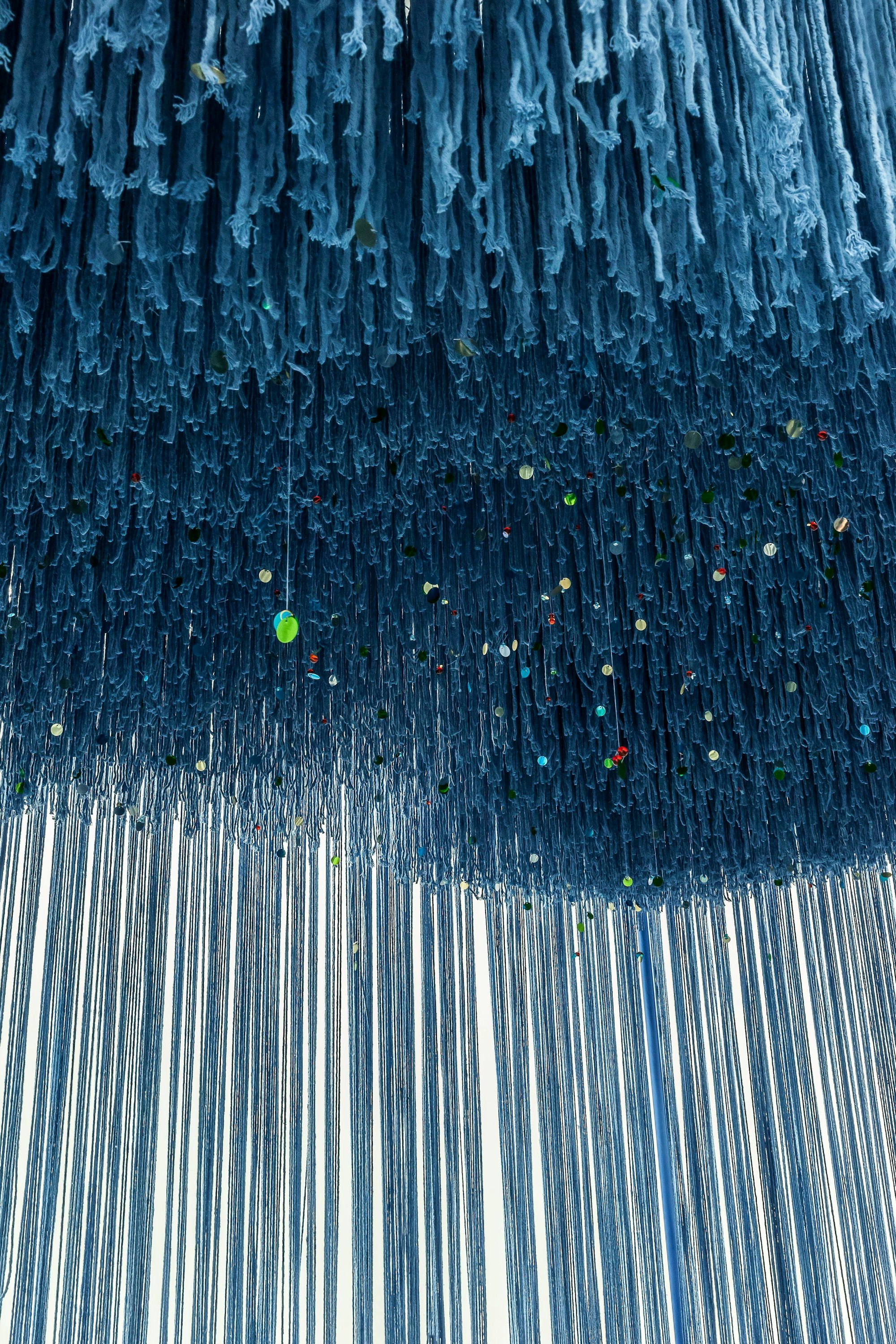 Eine dreidimensionale Malerei der türkischen Künstlerin Füsun Onur. Sie besteht aus langen blauen Wollfäden, die von der Decke hängen.