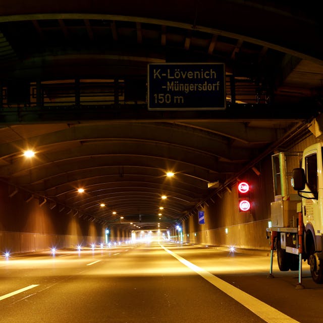 Der Autobahntunnel in Köln-Lövenich. Vorne rechts steht ein Wartungsfahrzeug. Ansonsten ist der nächtliche Tunnel aufgrund der Sperrung leer.