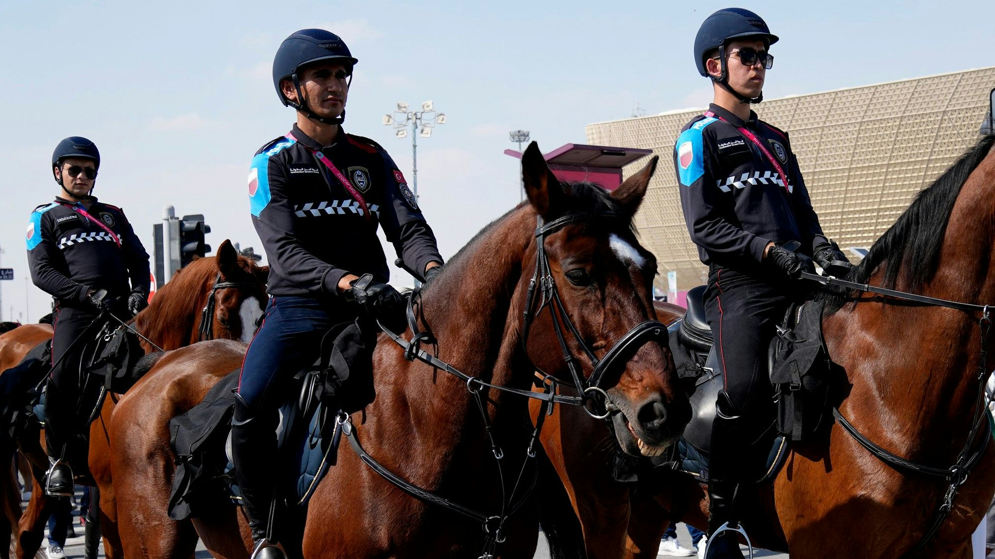 Katarische Polizisten begleiten einen Fanmarsch auf Pferden.