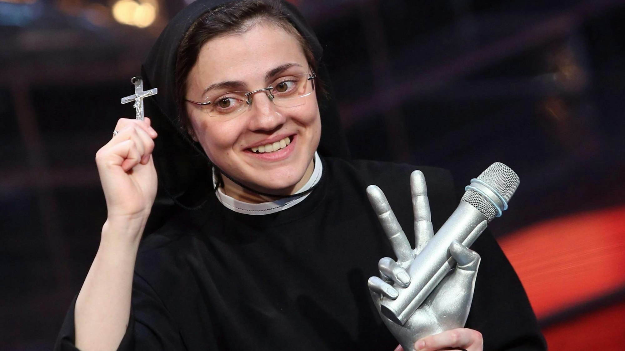 Die italienische Schwester Cristina Scuccia lächelt mit ihrem Preis in der Hand, nachdem sie das Finale des staatlichen RAI-Fernsehprogramms „The Voice of Italy“ in Mailand, Italien, am 05. Juni 2014 gewonnen hat. In der anderen Hand hält sie ein kleines Kruzifix hoch.