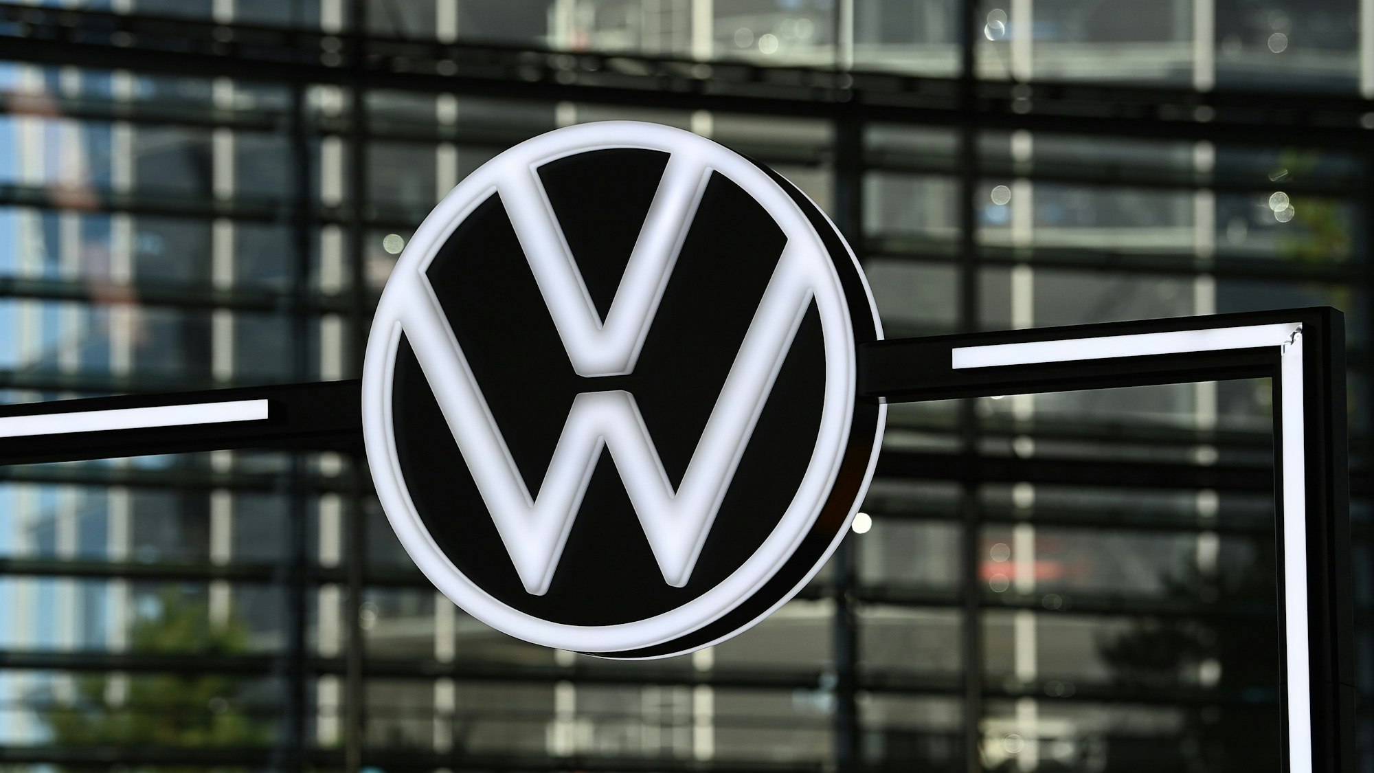 Ein Volkswagen Logo vor einer Glasfassade.