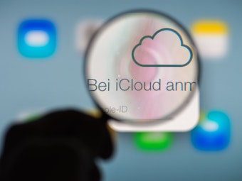 Eine Hand hält am 13.01.2014 in Straubing (Bayern) ein Vergrößerungsglas vor die Internetseite des Online-Speicherdienstes iCloud von Apple.