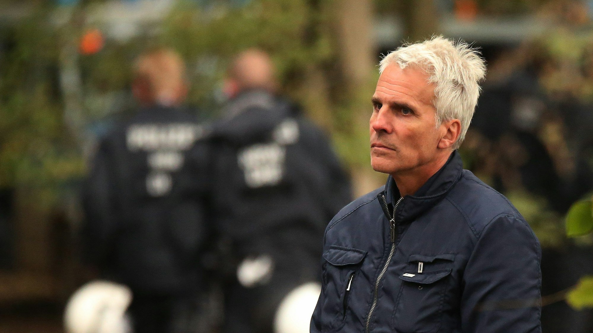 Dirk Weinspach ist während des Polizeieinsatzes im Hambacher Forst zu sehen. Er blickt an der Kamera vorbei, im Hintergrund sieht man weitere Polizeikräfte.