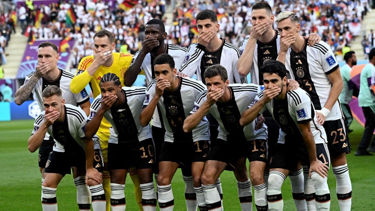 Die deutschen Nationalspieler halten sich beim Mannschaftsfoto den Mund zu.