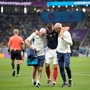 Frankreichs Lucas Hernández wird während des WM-Spiels der Gruppe D zwischen Frankreich und Australien im Al-Janoub-Stadion in Al Wakrah, Katar, vom Platz gebracht. Zwei Mitarbeiter des Ärzeteteams stützen ihn.