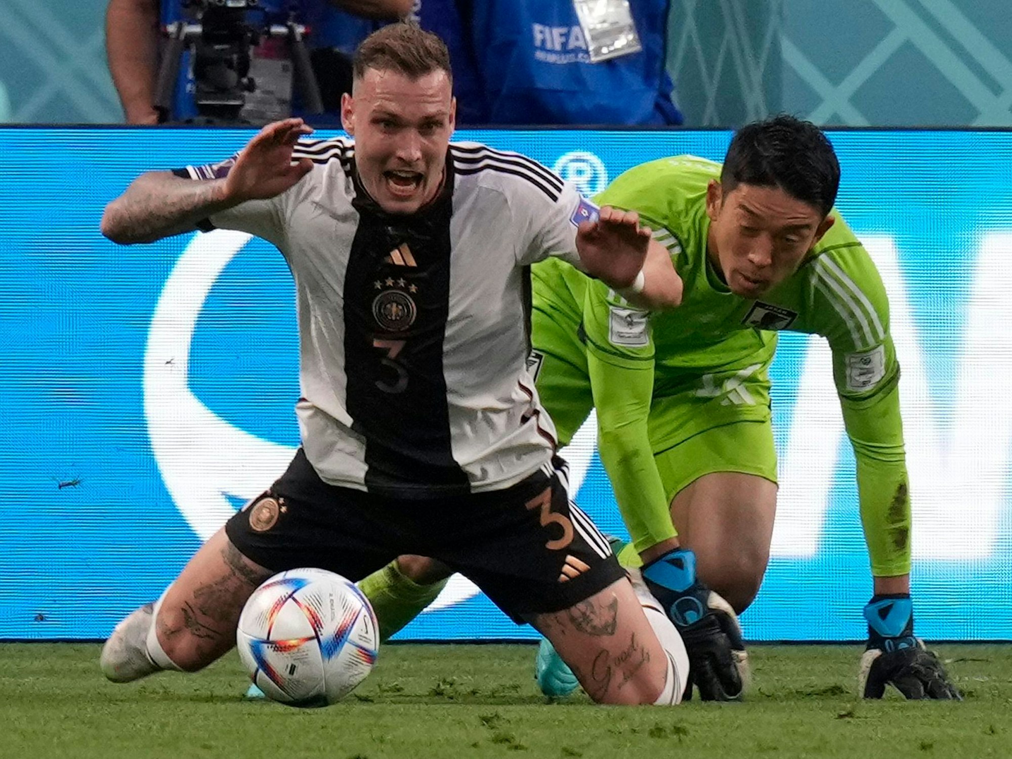 Germany's David Raum, left, fights for the ball with Japan's goalkeeper Shuichi Gonda during the World Cup group E soccer match between Germany and Japan, at the Khalifa International Stadium in Doha, Qatar, Wednesday, Nov. 23, 2022. (AP Photo/Eugene Hoshiko)
