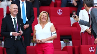 Bundesinnenministerin Nancy Faeser (SPD) und DFB-Präsident Bernd Neuendorf stehen auf der Tribüne bei der Fußball-WM in Katar und werden von einem Mann fotografiert. Faeser trägt die One-Love-Armbinde, die die Fifa kurz zuvor für Spieler untersagt hatte.