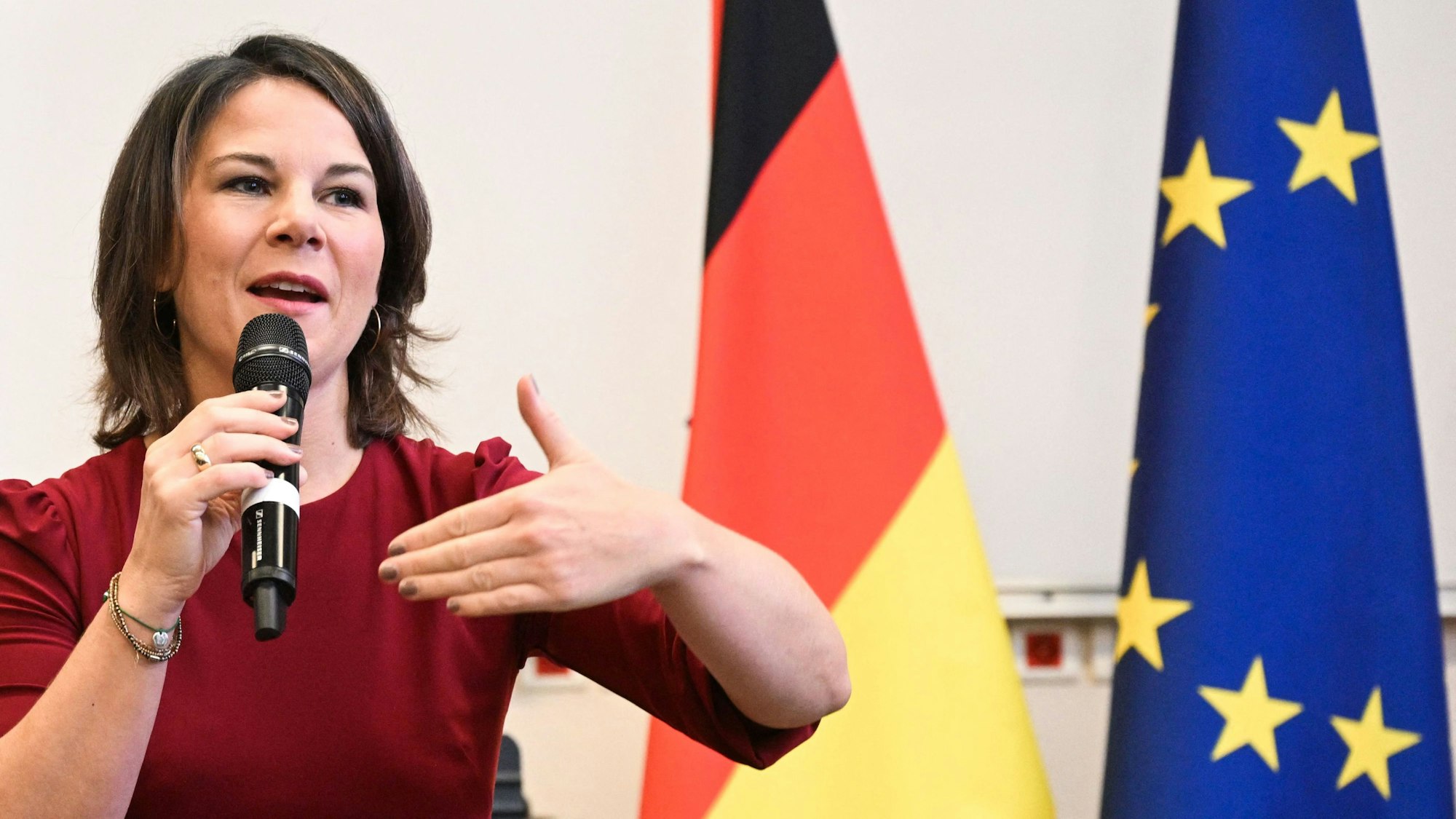 Annalena Baerbock spricht auf einer Konferenz. Im Hintergrund sind eine Europa- und eine Deutschlandflagge.