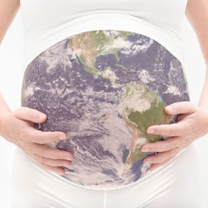 Eine schwangere Frau hält ihren Bauch, der aussieht wie die Erdkugel.