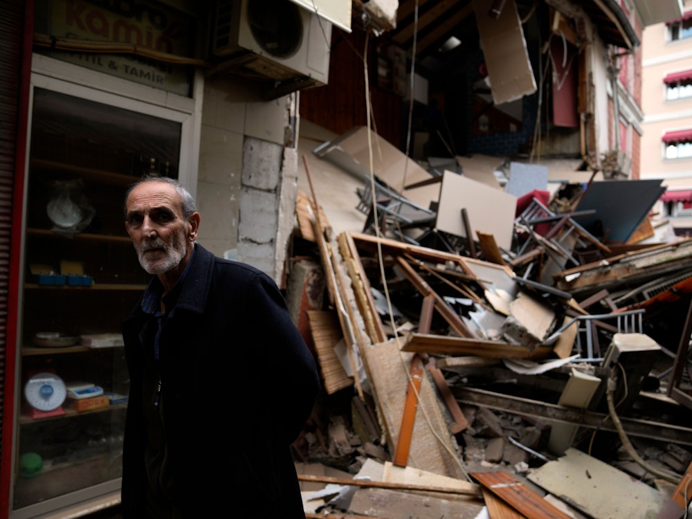 Ein Mann geht durch einen Teil beschädigter Geschäfte, nach einem Erdbeben.