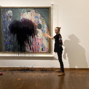 Ein Aktivist wirft schwarze Farbe auf ein Gemälde in einem Museum.