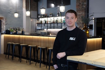 Betriebsleiter David Pick steht in der neuen Cocktailbar „Der Schwarze Hase“ in Köln-Ehrenfeld an einem Bartisch.