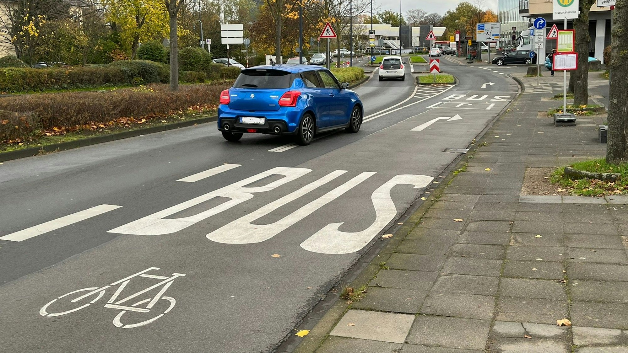 Ein Auto biegt auf eine Fahrspur, die für Busse und Fahrräder gekennzeichnet ist.