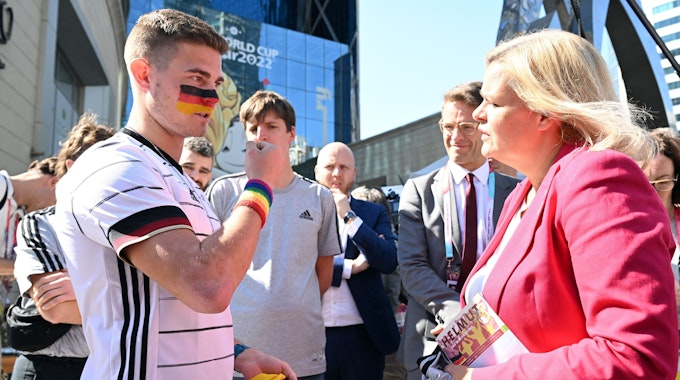 Der Kölner Student Bengt Kunkel im Gespräch mit der Bundesinnenministerin Nancy Faser. Kunkel trägt ein Schweißband mit Regenbogenfarben.