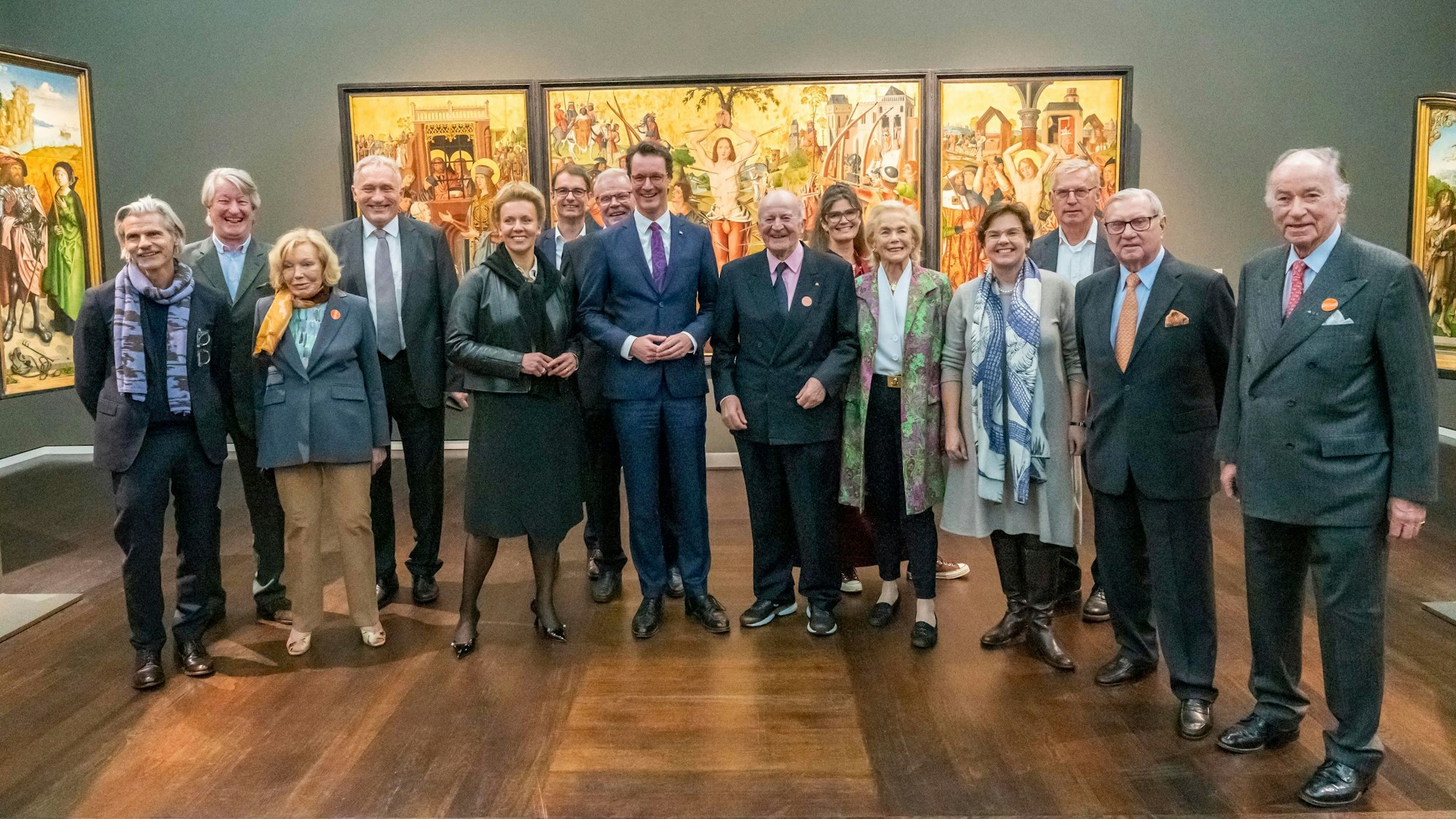 Ministerpräsident Hendrik Wüst und Mitglieder des Stifterrats stehen im Wallraf-Richartz-Museum vor einem mittelalterlichen Gemälde.