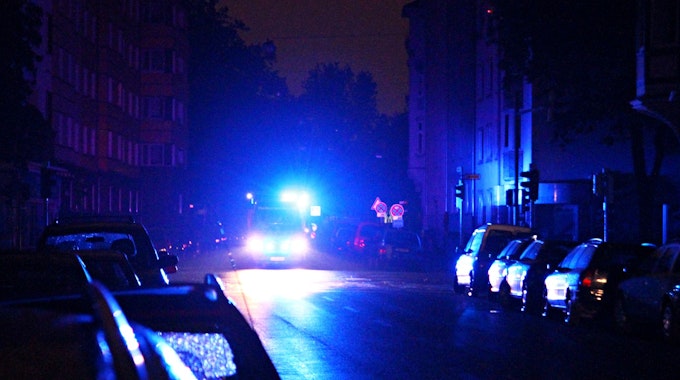 Ein Rettungswagen fährt während eines Stromausfalls mit Blaulicht durch eine dunkle Straße.