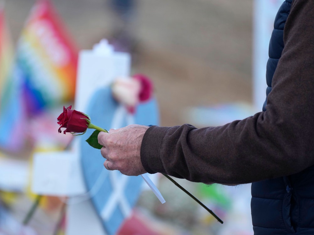 Ein Mann legt eine Rose auf eine Gedenkstätte.