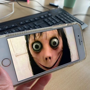 Ein Bild der Gruselfigur Momo ist auf einem Handy zu sehen.