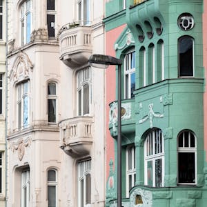 Pastellfarbene Altbauten stehen an einer Straße in Köln.