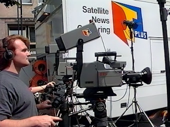 Das Bild zeigt einen jungen Mann mit einer großen, mobilen Filmkamera.