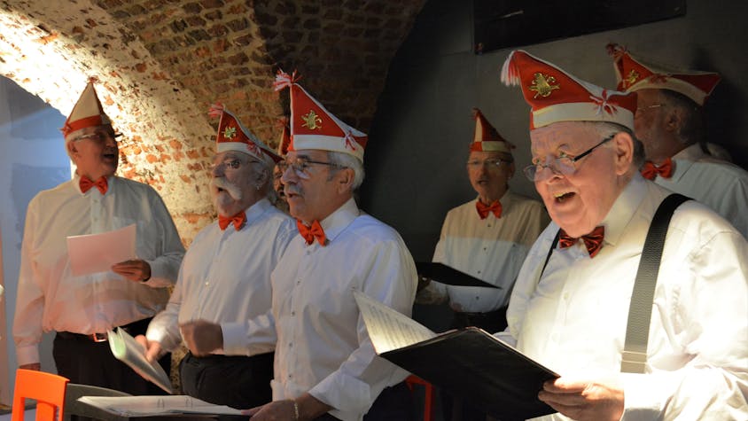 Der Chor der Roten Funken, bekleidet im weißen Hemd und rot-weißen Mützen, singt das erste Karnevalslied Kölns in der Ulrepforte.
