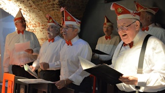 Der Chor der Roten Funken, bekleidet im weißen Hemd und rot-weißen Mützen, singt das erste Karnevalslied Kölns in der Ulrepforte.