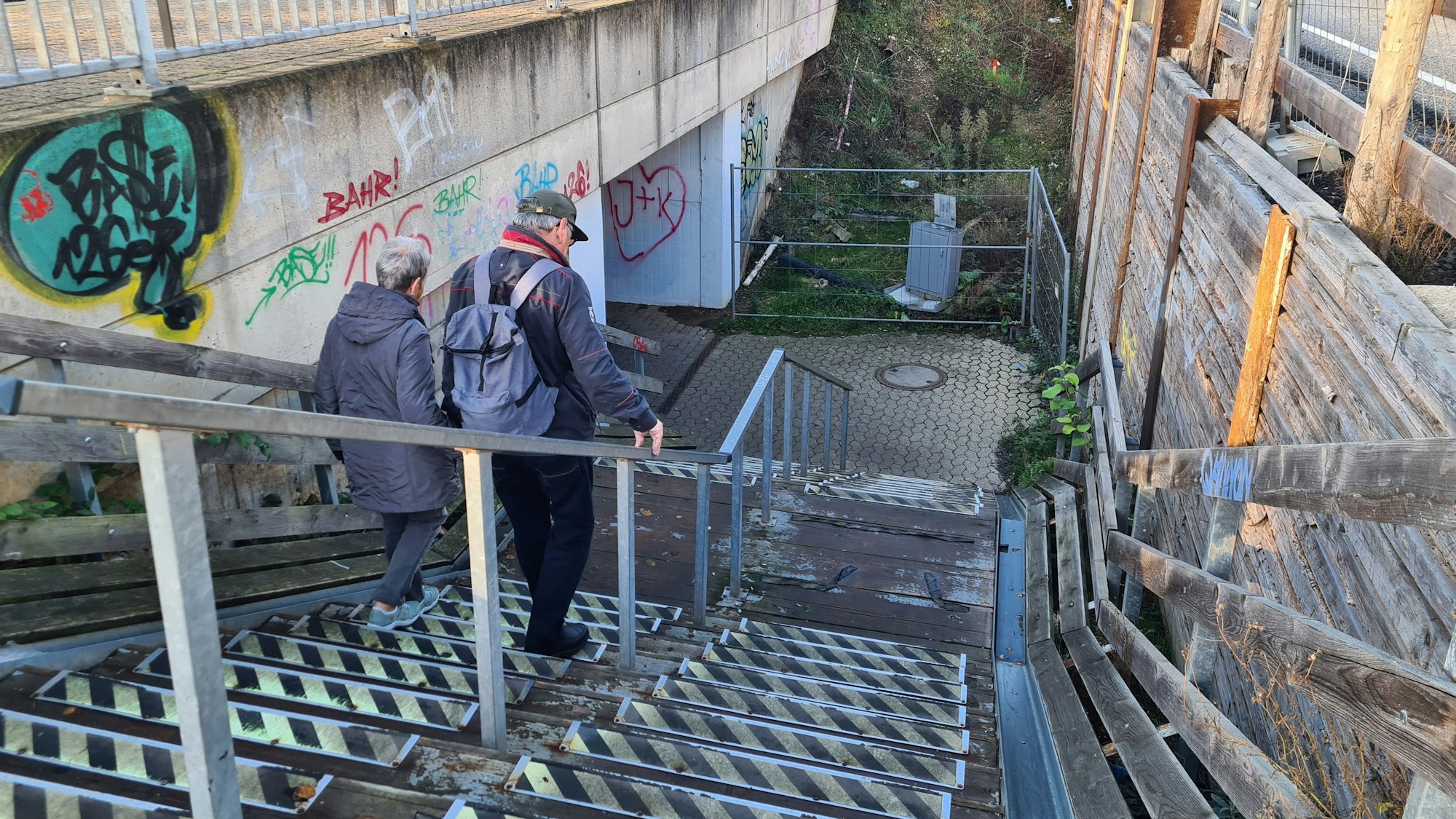 Das Foto zeigt eine Treppe am Bahnhof Bergheim, die zu den Bahnsteigen führt. Eine Frau und ein Mann gehen die Stufen herunter.