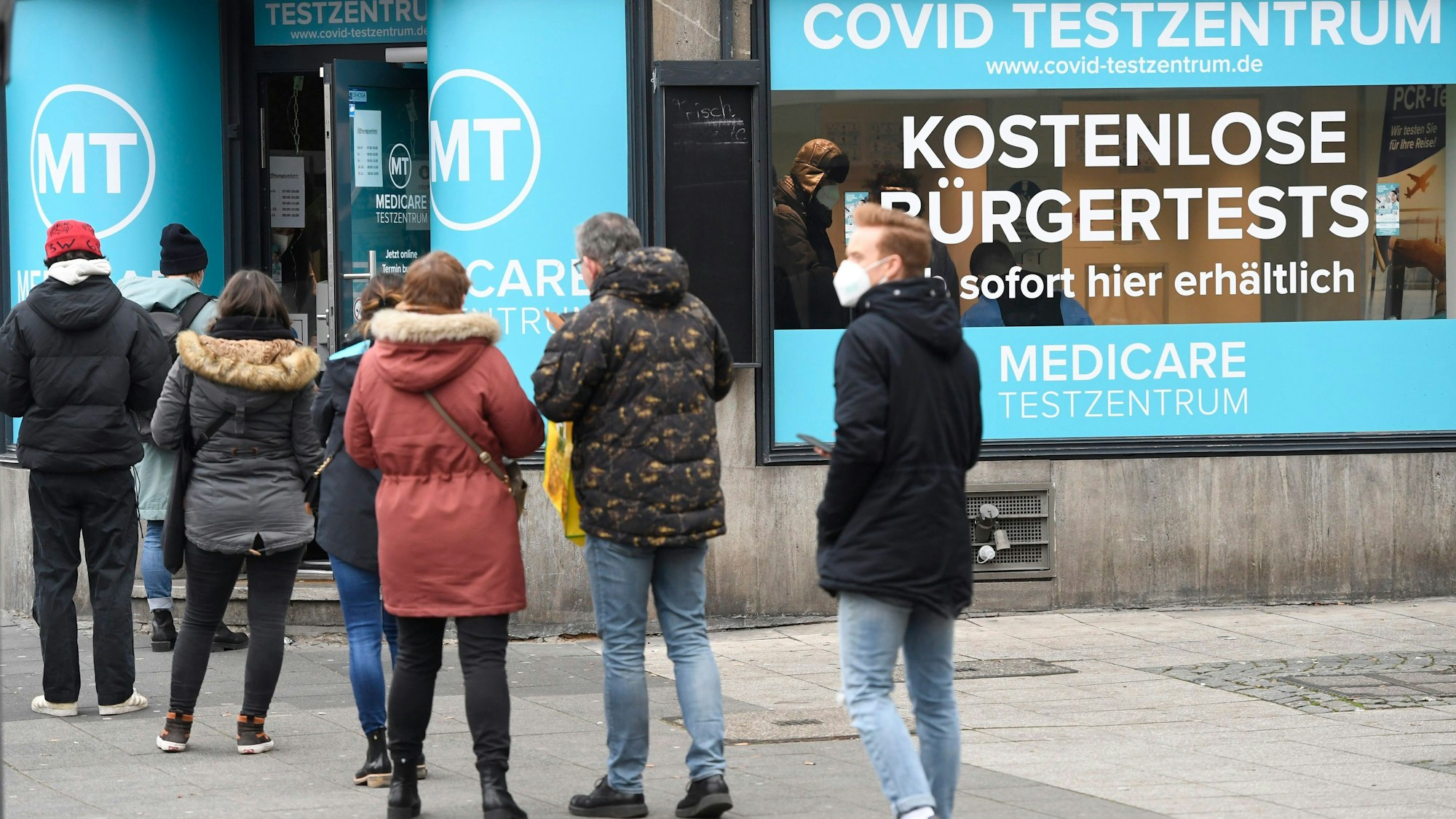 Menschen stehen vor dem Testzentrum am Ebertplatz in Köln Schlange, um sich einen aktuellen Covid-19-Test zu besorgen.