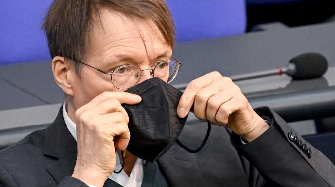 Bundesminister für Gesundheit, setzt seine Maske nach seiner Rede bei der Sitzung im Bundestag wieder auf.
