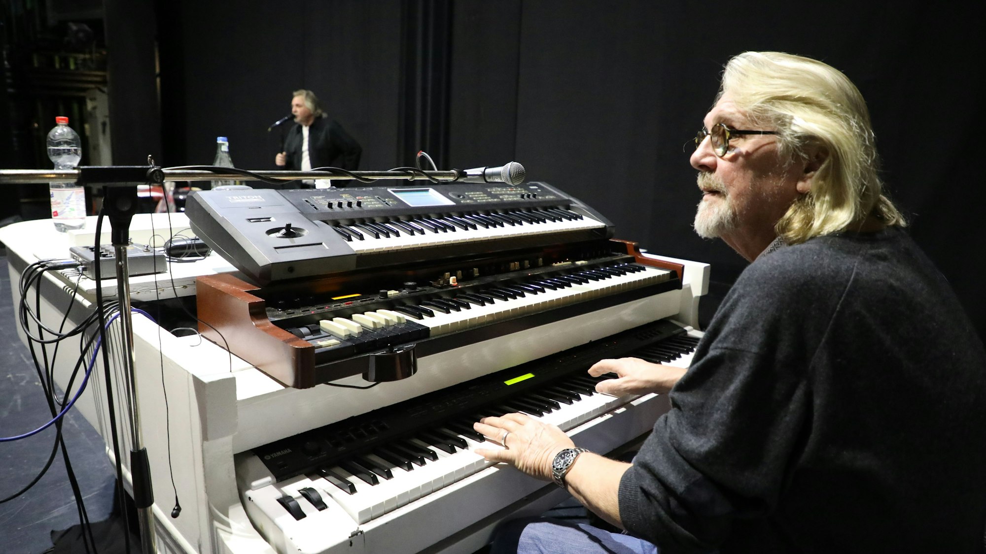 Pianist Jürgen Fritz sitz an einem weißen Flügel mit E-Pianos und Keyboards.