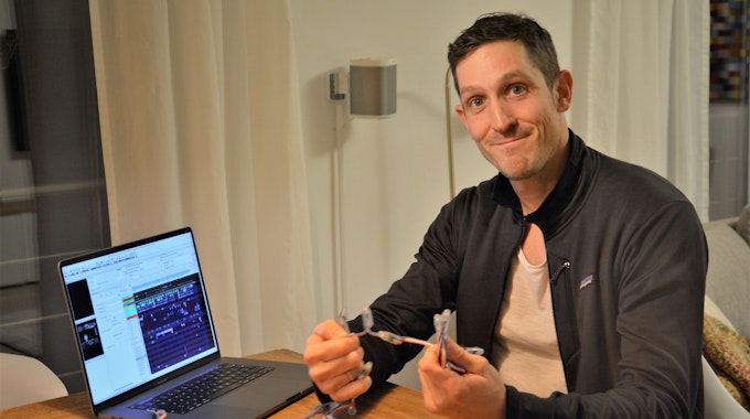 Simon Biela aus Köln-Müngersdorf in seiner Wohnung vor dem Laptop, an dem er die Lichtshow programmiert hat. In der Hand hält er eine der Lichterketten.