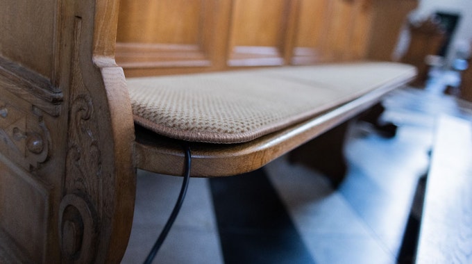 Ein beheiztes Sitzkissen (ein Prototyp) liegt auf einer Bank in der St. Mariä Himmelfahrt Kirche.