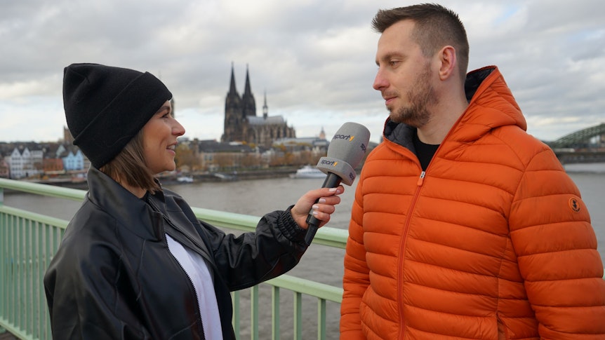 Sport1-Moderatorin Jana Wosnitza (l.) am Mittwoch (23. November 2022) im Gespräch mit Darts-Profi Florian Hempel auf der Deutzer Brücke.