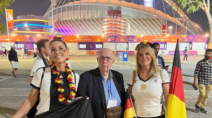 Reiner Calmund, der ein dunkelblaues Sakko trägt, lässt sich nach dem WM-Spiel zwischen Deutschland und Japan mit den deutschen Fans Elena (l.) und Elke Stegili vor dem Khalifa International Stadions in Al-Rayyan fotografieren.