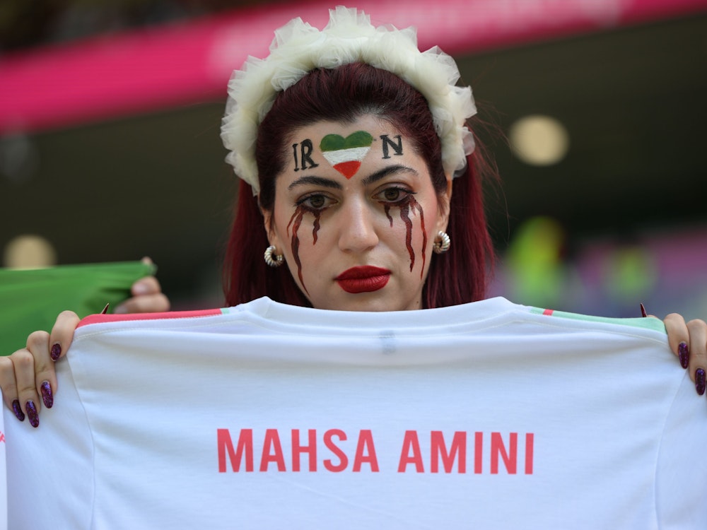 Eine Frau aus dem Iran hält vor dem Spiel ein Trikot mit der Aufschrift der verstorbenen iranischen Kurdin „Mahsa Amini“.