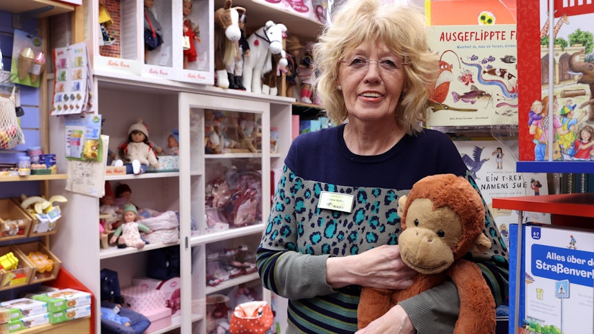 Cristina Steffen steht in ihrem Spielzeugladen und hält einen ausgestopften Affen im Arm.