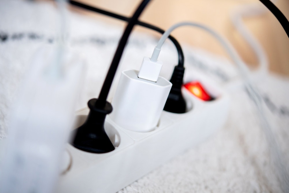 Die Netzstecker mehrerer Elektrogeräte stecken in einer Steckdosenleiste in einem Wohnzimmer. Viele Stromversorger erhöhen die Preise ab Januar 2023.