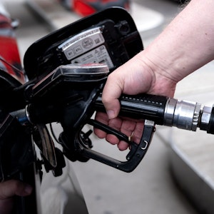 Ein Mann hält eine Zapfpistole an einer Tankstelle in der Hand und betankt sein Auto.