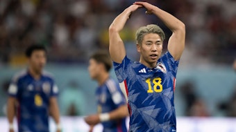 Der japanische Nationalspieler Takuma Asano animiert die Zuschauer zum Jubeln, indem er beide Arme nach oben reißt.