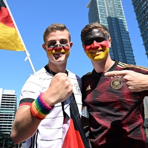 Die Deutschland-Fans Bengt (l.) und Jan Kunkel posieren mit einem regenbogenfarbenen Schweißband für die Kamera.