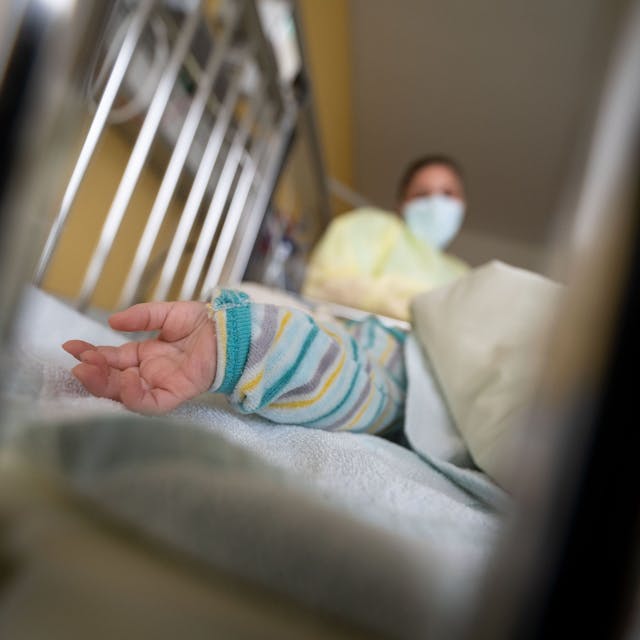 Ein am Respiratorischen Synzytial-Virus (RS-Virus oder RSV) erkrankter Patient liegt auf einer Kinderstation des Olgahospitals des Klinkums Stuttgart in einem Krankenbett. Vorne ist eine Kinderhand, im Hintergrund ist eine Krankenschwester.