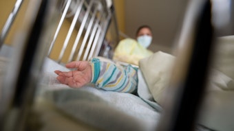 Ein am Respiratorischen Synzytial-Virus (RS-Virus oder RSV) erkrankter Patient liegt auf einer Kinderstation des Olgahospitals des Klinkums Stuttgart in einem Krankenbett. Vorne ist eine Kinderhand, im Hintergrund ist eine Krankenschwester.